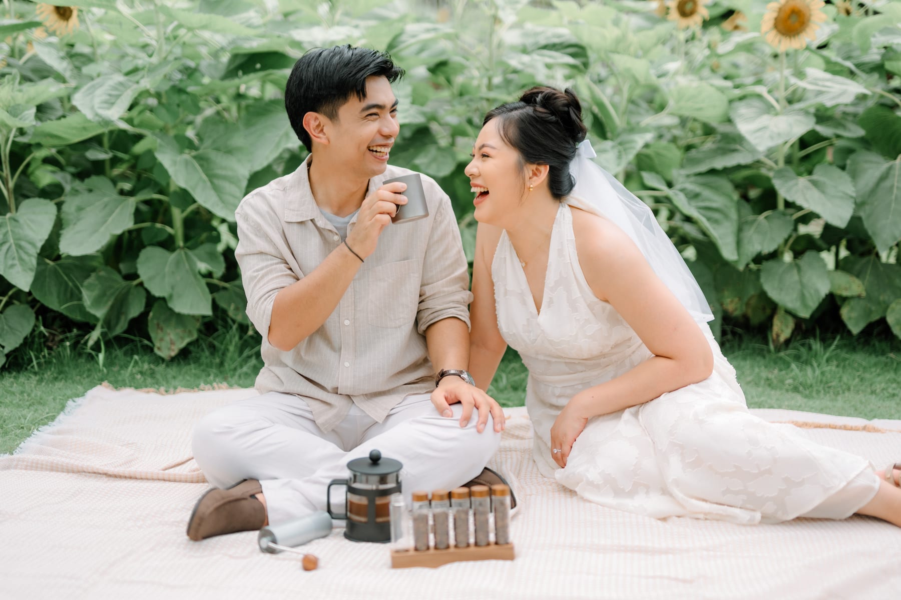 Luis and Tricia sharing coffee on a picnic blanket among the sunflowers